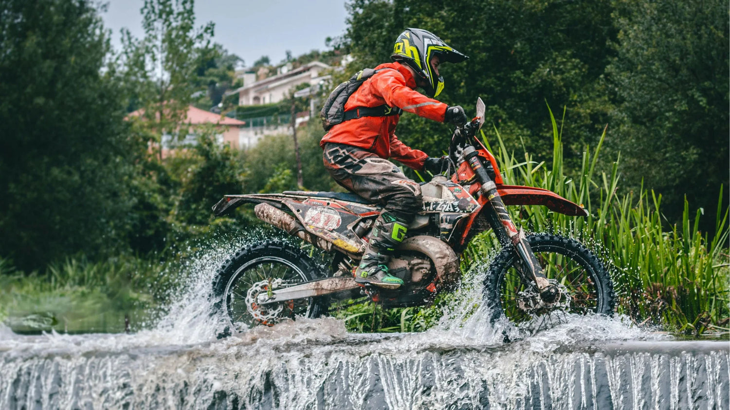 Adventure motorrijder in beschermende motorkleding tijdens offroad rit door water – ideale uitrusting voor elke rijstijl en elk seizoen